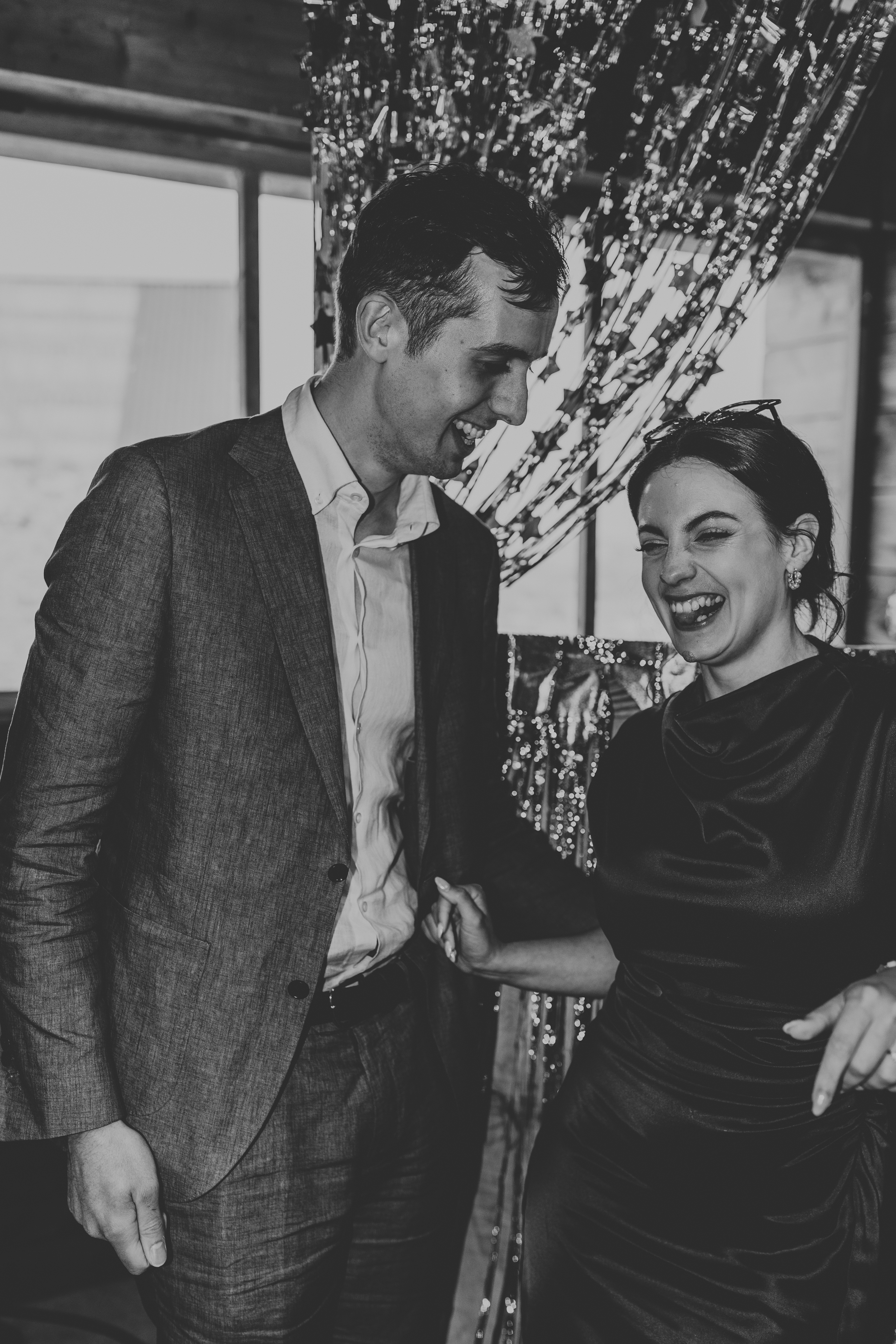 Joe and Naomi, stood in a forest, holding eachother's hands, smiling and laughing
